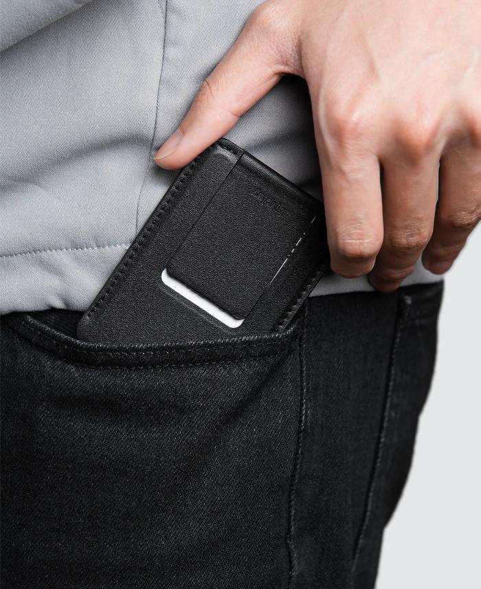 Person inserting a black Bitplay Magnetic Ultra Slim Wallet Stand onto his pocket.