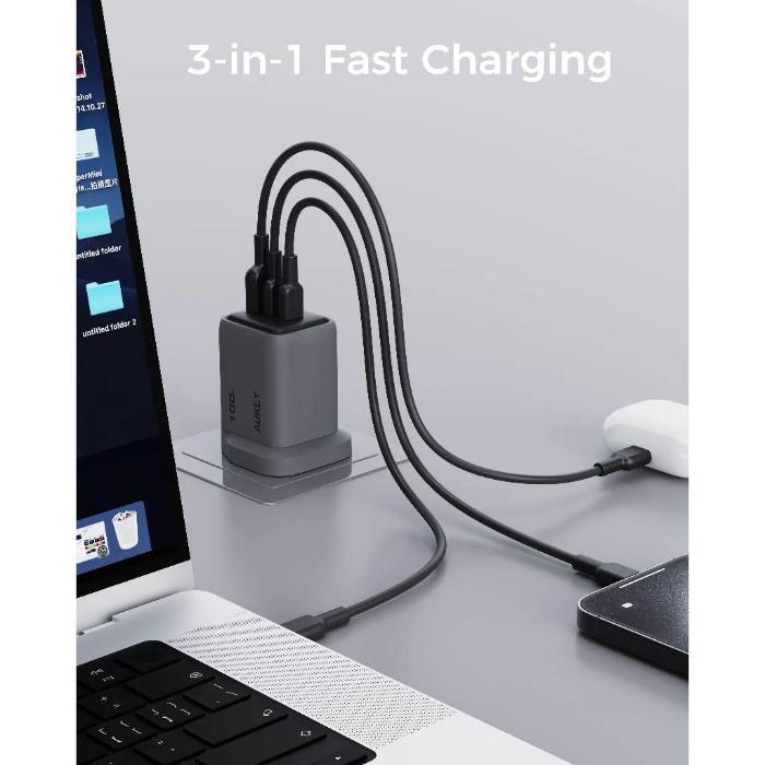 Gray Aukey PA-C5 Comet Mix 3 100W PD Wall Charger with GaN Technology charging 3 devices at the same time - laptop, AirPods and phone on a gray surface