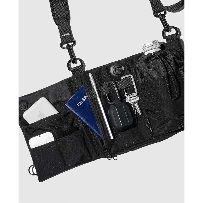 Black Bitplay Black Series Sacoche 2L Crossbody Bag/Chest Bag with various items including a phone, keys, and a passport on a light gray background.