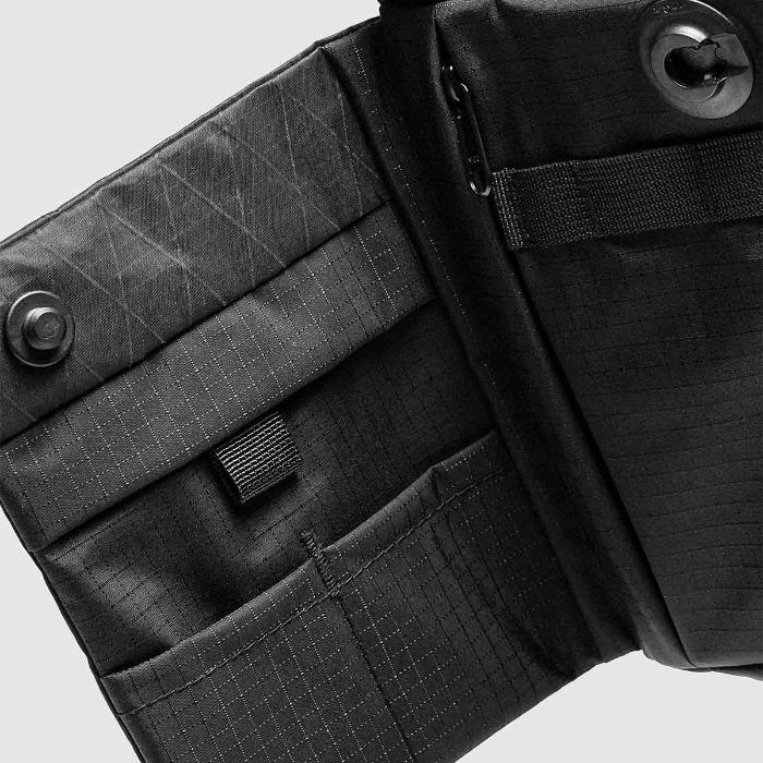 Close-up of a Black Bitplay Black Series Sacoche 2L Crossbody Bag/Chest Bag with zippers and straps on a light gray background