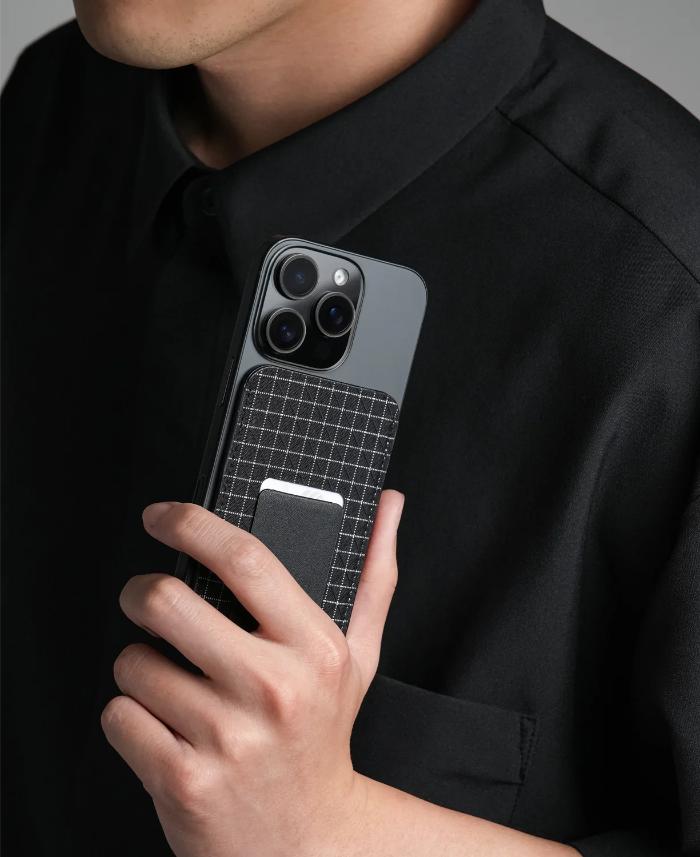 Person holding a phone with a grid Bitplay Magnetic Ultra Slim Wallet Stand against a dark background