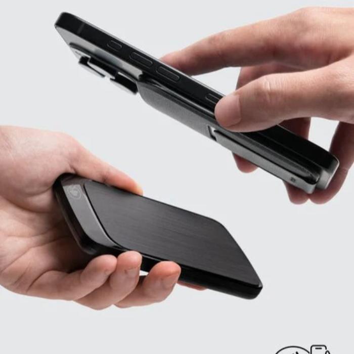Two hands holding a  phone with a Bitplay Magnetic Ultra Slim Wallet Stand against a light gray background