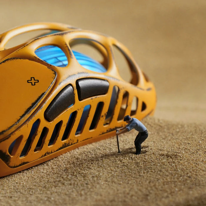 Yellow Gravastar Mercury X Wireless Gaming Mouse on sand, small figure standing next to it.