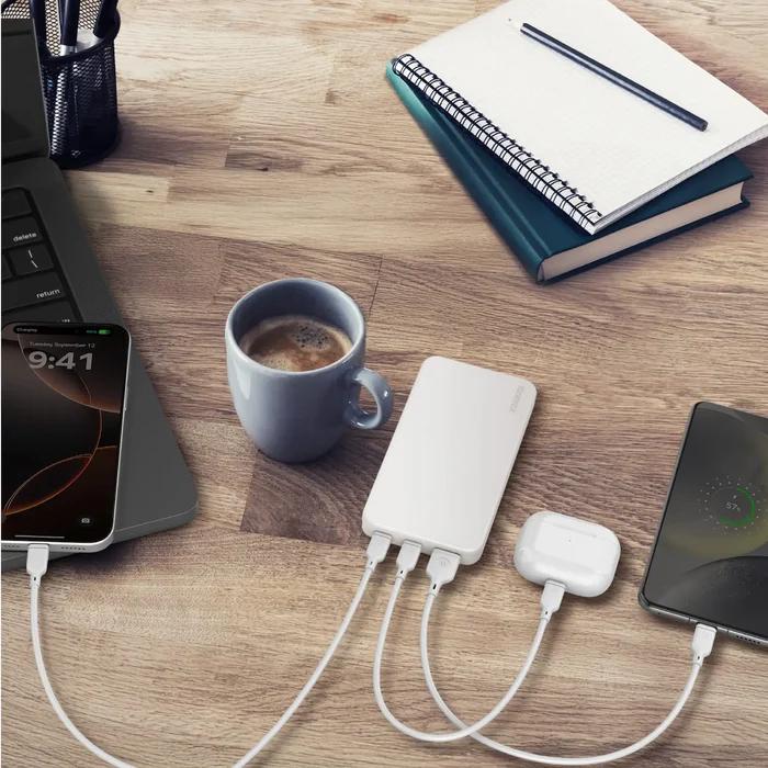 White Momax IP155W 10000mAh 1-Power Vital Battery Pack with multiple cables on a desk with a cup of coffee, smartphone, and notebook.